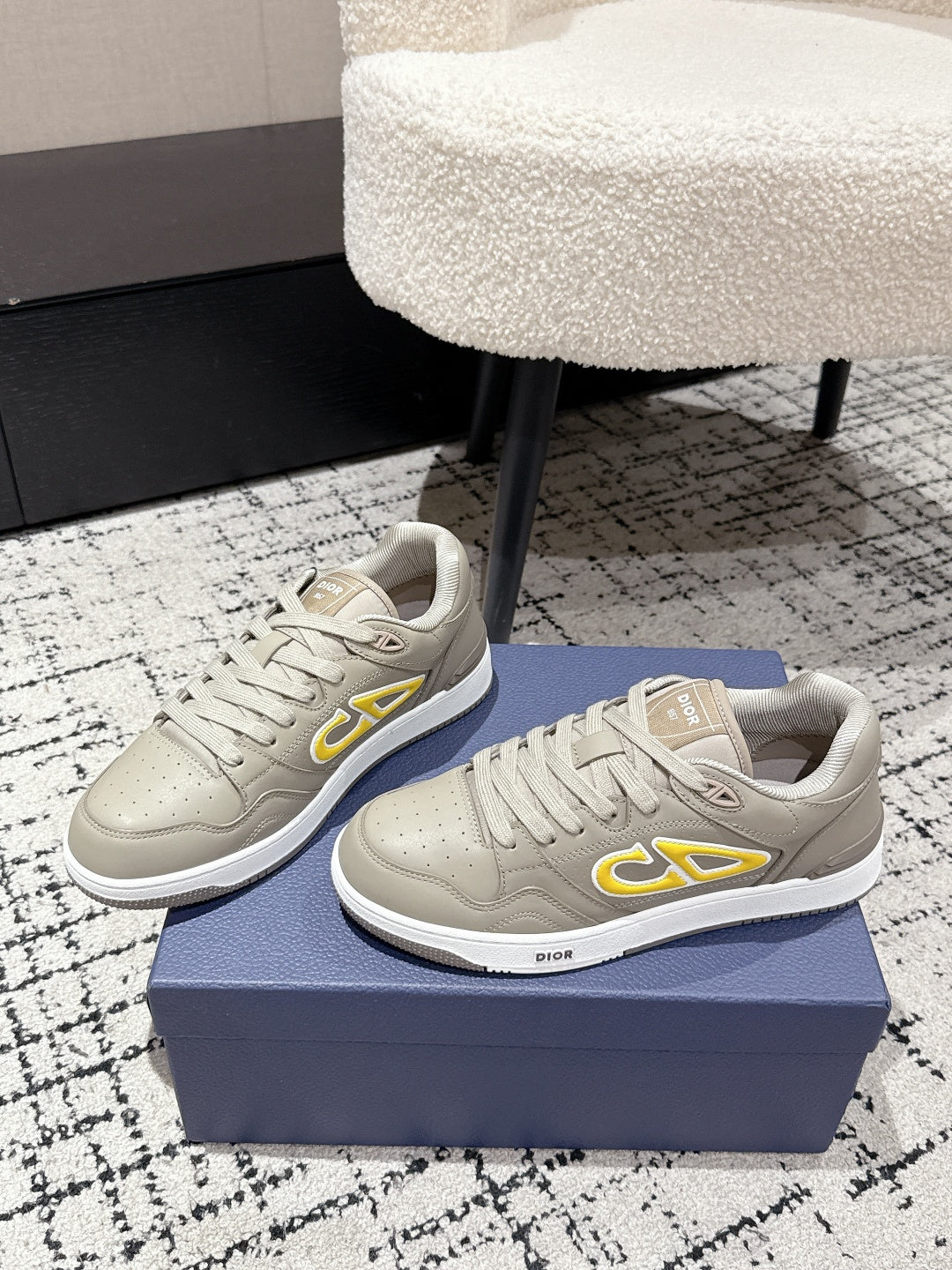 Beige Dior low-top sneakers pair, side profile with yellow logo accents