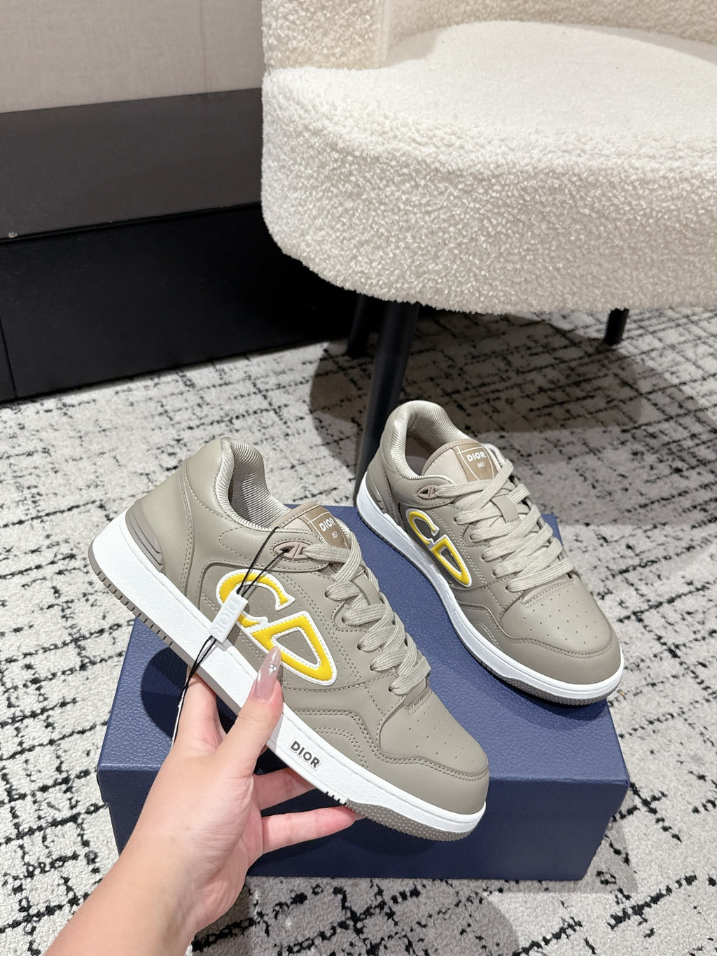 Beige Dior lace-up sneakers with yellow logo, close-up on blue box