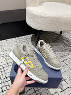 Beige Dior lace-up sneakers with yellow logo, close-up on blue box