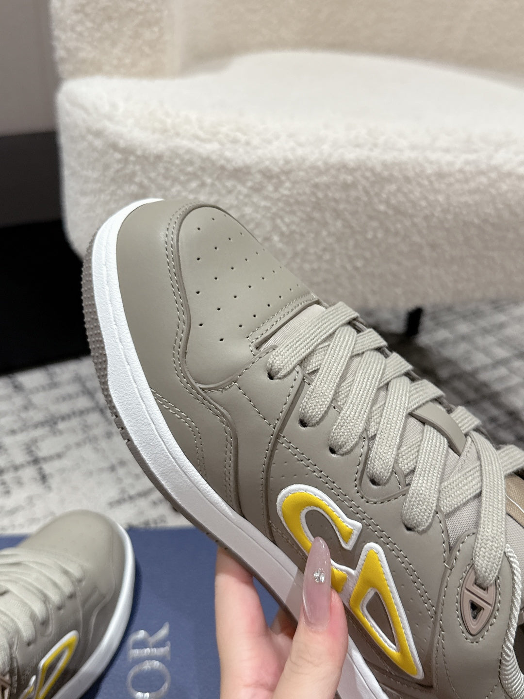 Beige Dior sneaker toe and side panel, close-up of yellow logo