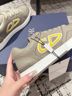 Beige Dior low-top sneaker side view with yellow logo strap and laces