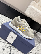Beige Dior lace-up sneakers with side yellow logo, shown on blue box