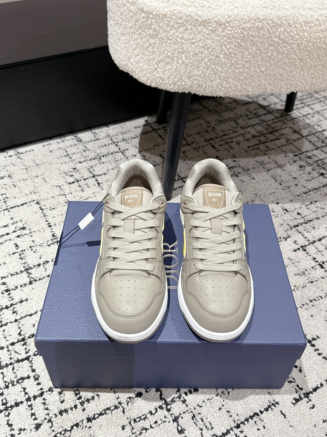 Beige Dior low-top sneakers with yellow logo, lace-up front view