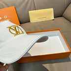 White baseball cap showing gold monogram logo and side curve of the brim