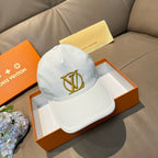 White baseball cap with gold Louis Vuitton-style monogram on the front panel