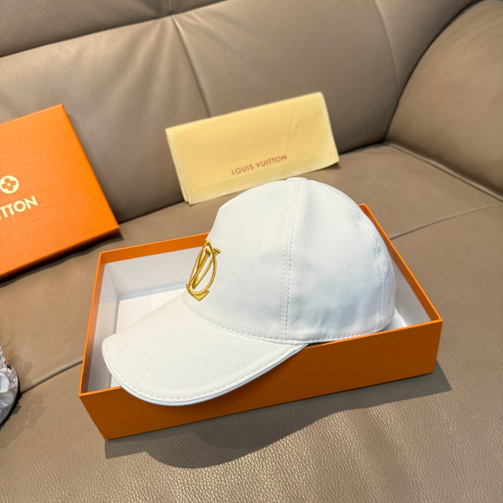 Light blue baseball cap with gold monogram logo on the front, curved brim