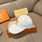 Light blue baseball cap with gold monogram logo on the front, curved brim