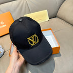 Louis Vuitton black cap with gold LV emblem, held in hand