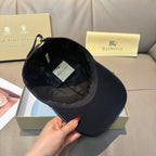 Black Burberry baseball cap shown open, with interior stitching and hanging tag.