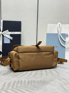 Tan duffel-style handbag with front flap and gold hardware, back view