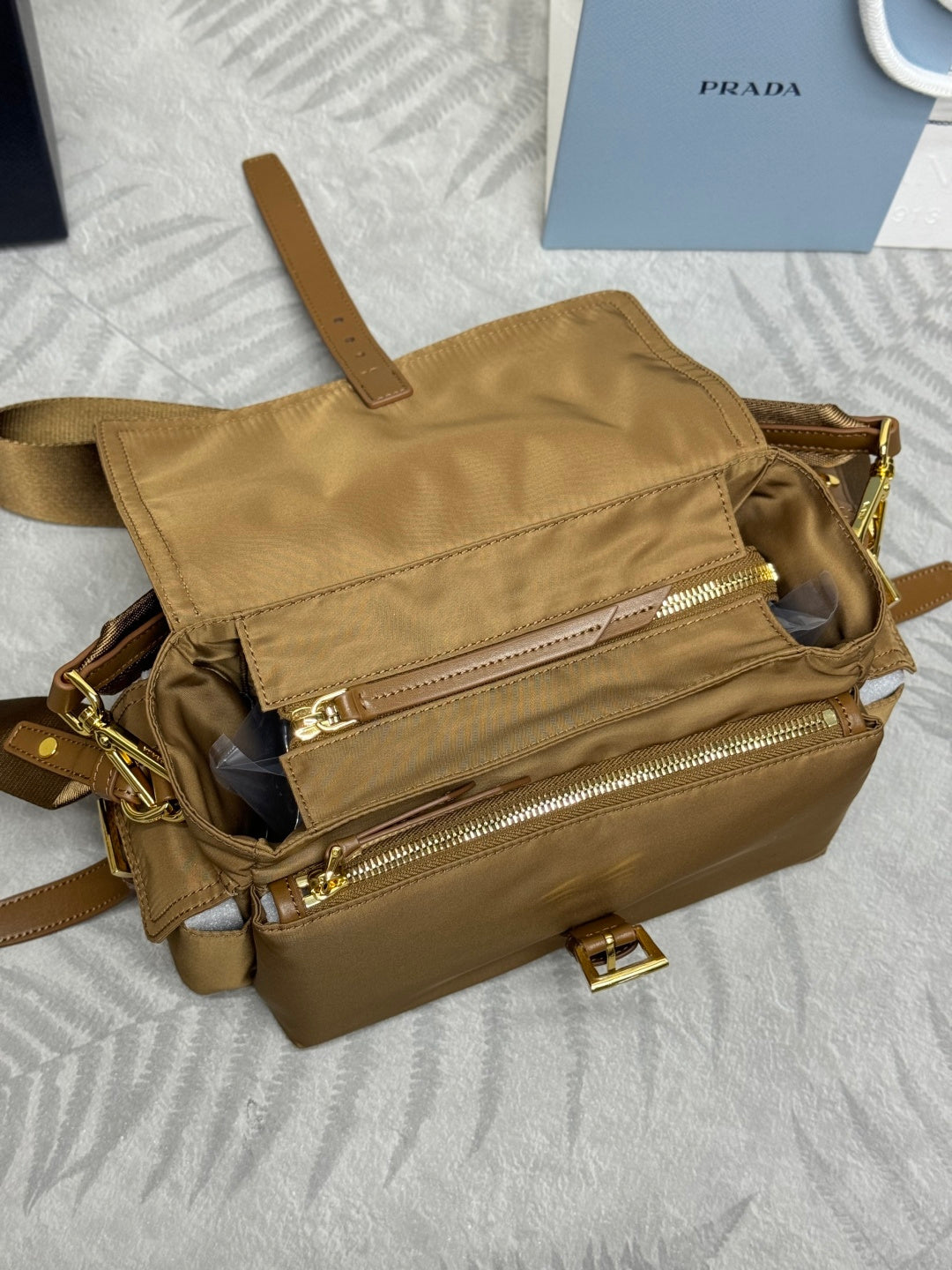 Tan handbag with open top, front zip pocket, and gold zipper pulls, close angle