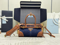 Prada handbag with navy denim body, tan leather trim, top handle, and gold hardware