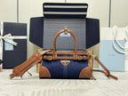Prada handbag with navy denim body, tan leather trim, top handle, and gold hardware
