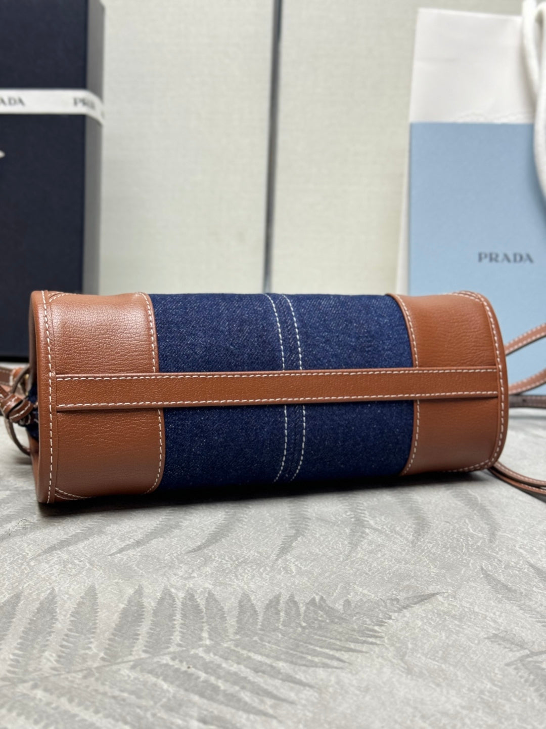 Prada handbag with rolled navy denim body and tan leather trim, front flap detail