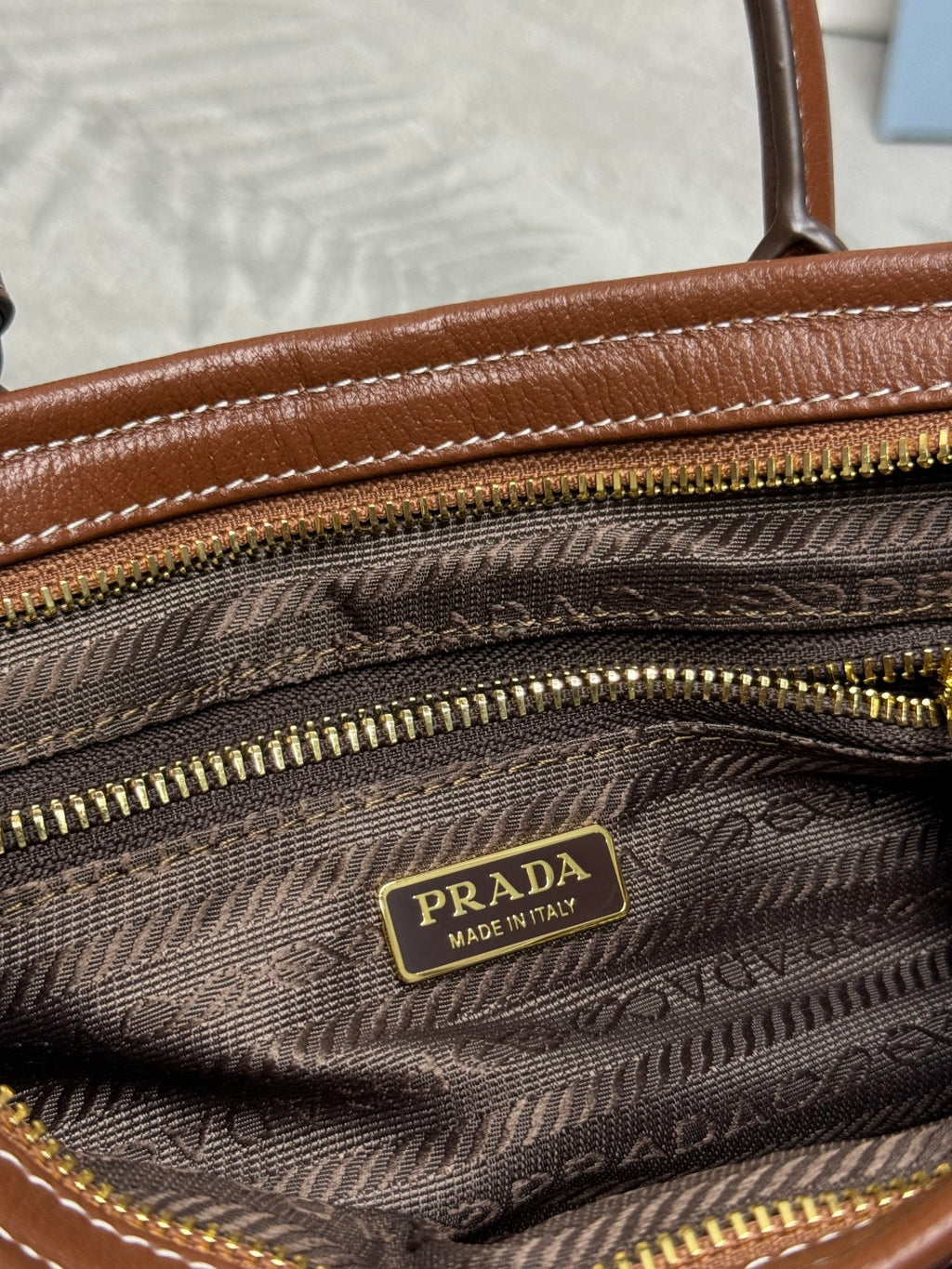 Prada denim handbag interior lining with Prada logo patch and multiple gold zippers