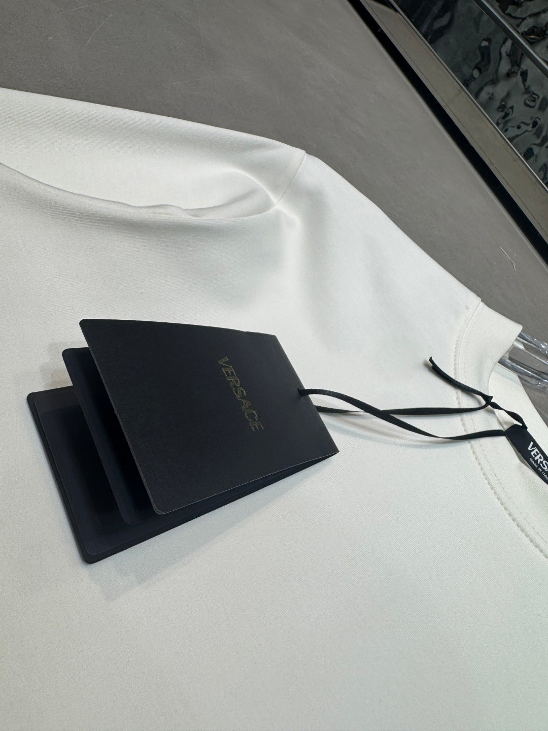 White long-sleeve T-shirt with VERSACE print and black hang tags