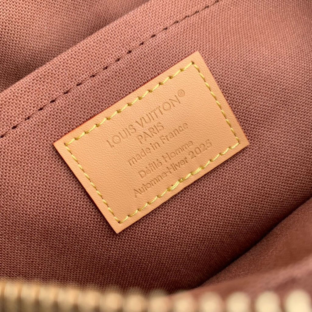 Louis Vuitton interior fabric label with tan stitched border on pink-brown lining