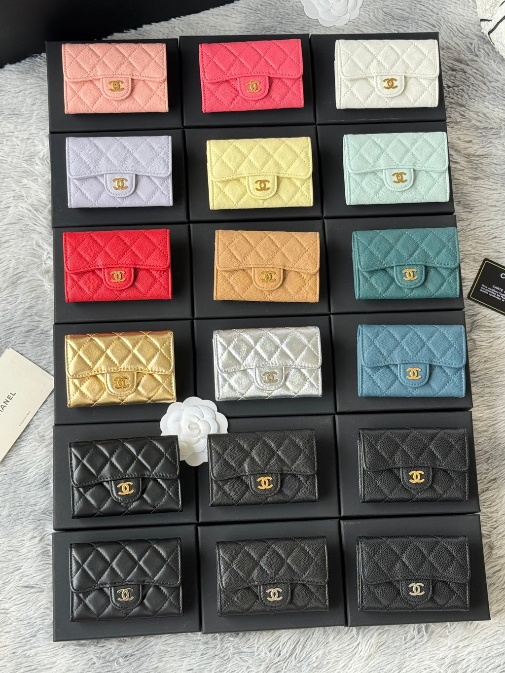 Small quilted flap wallet bags set in pink, red, white, yellow, teal, and black with logos.