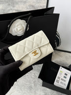 Quilted flap bag with gold logo, white textured leather, magnetic snap closure.