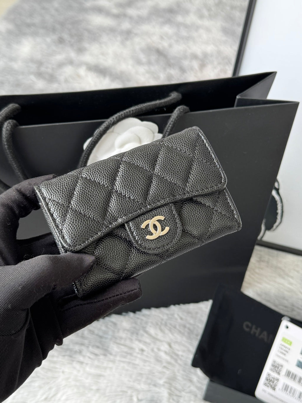 Small quilted flap bag in dark gray/black with front button and gold-tone logo.