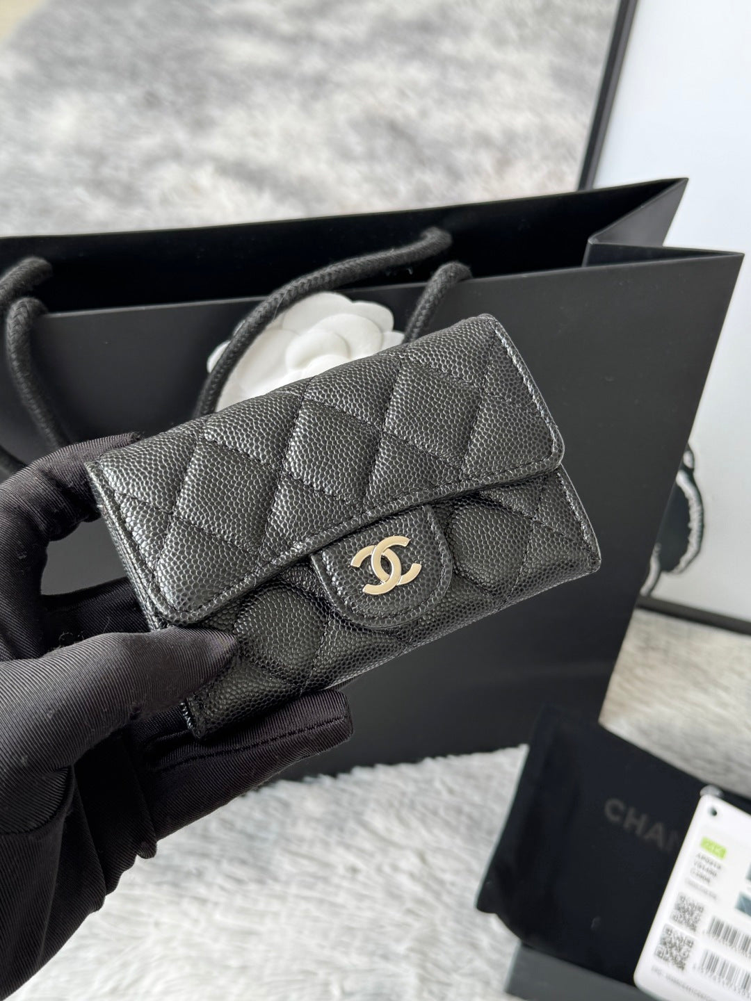 Small quilted flap bag in dark gray/black with front button and gold-tone logo.