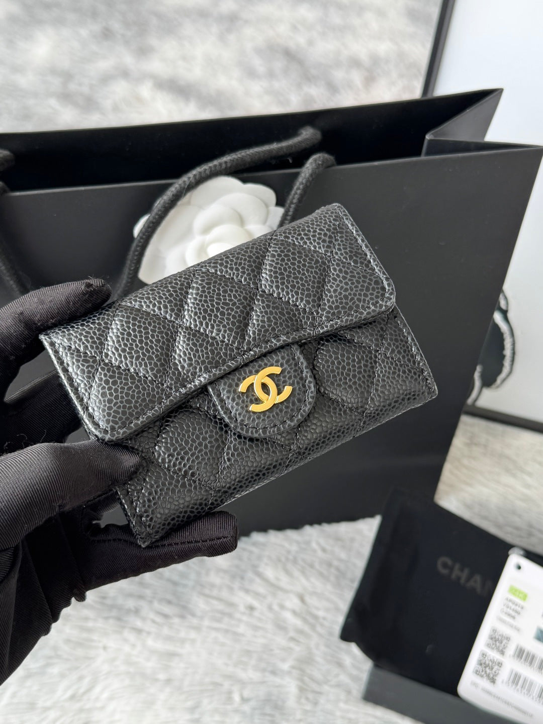 Small quilted flap bag in dark gray/black with gold-tone logo and curved flap.