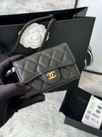 Small quilted flap bag in dark gray/black with gold-tone logo on front.
