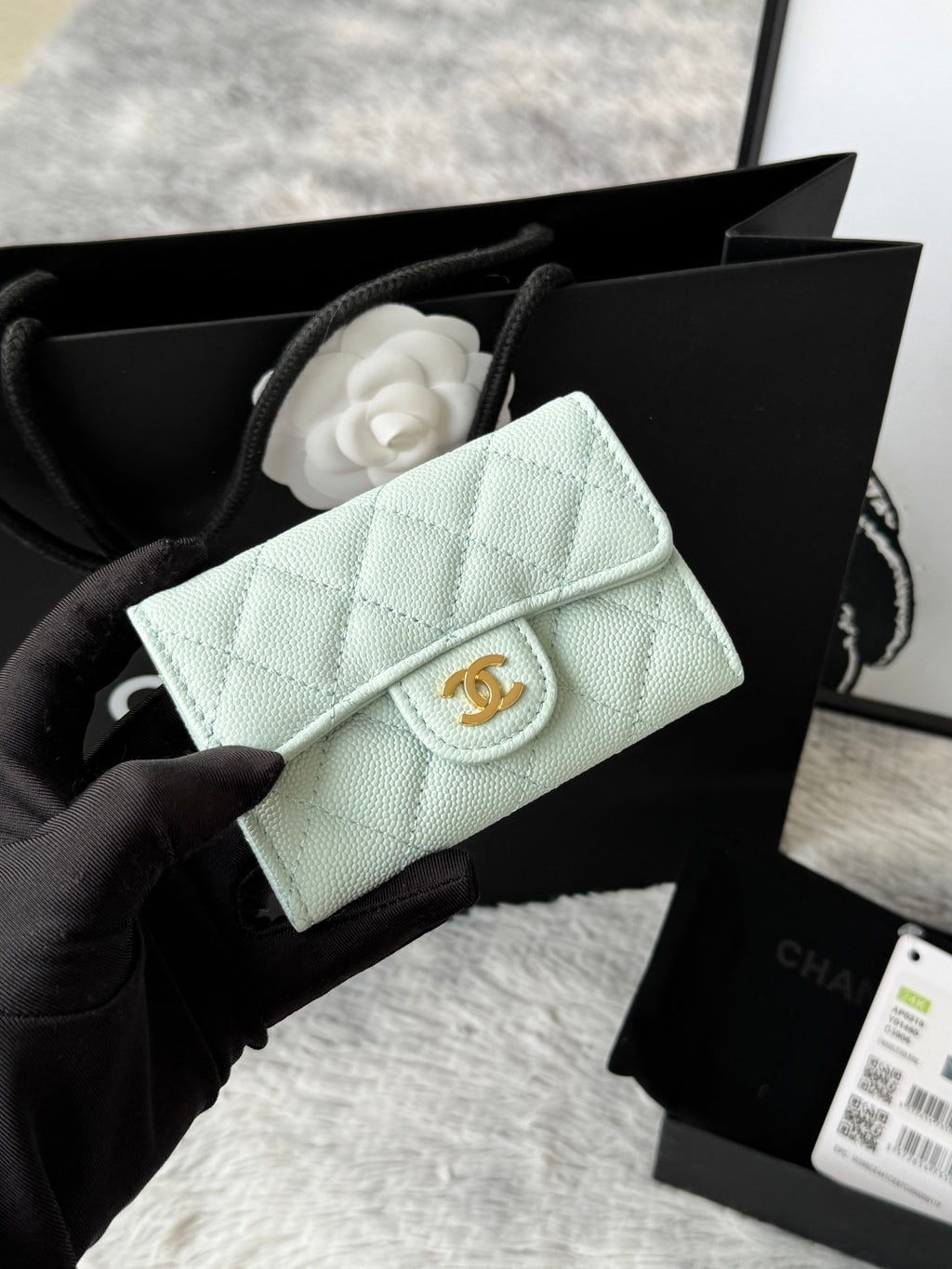 Quilted flap bag with gold logo, mint green textured leather, magnetic snap closure.