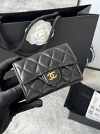 Small quilted flap bag in dark gray/black with gold-tone logo and structured top flap.