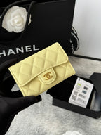 Small quilted flap wallet bag in light yellow with gold logo clasp and chain strap.