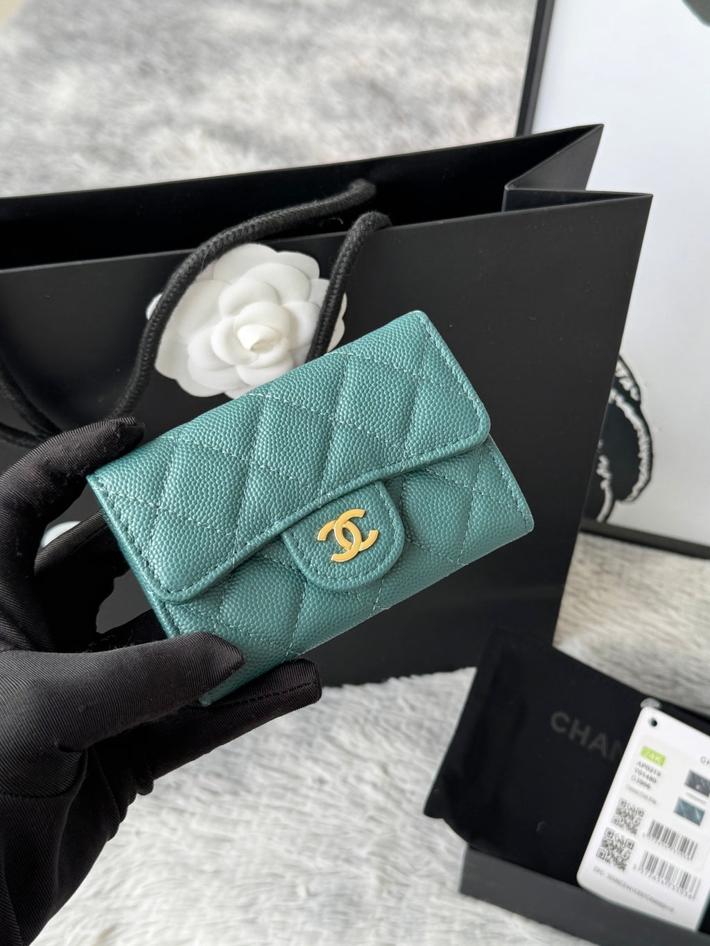 Quilted flap bag with gold logo, turquoise textured leather, magnetic snap closure.