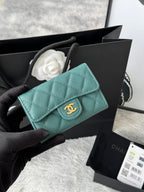 Quilted flap bag with gold logo, turquoise textured leather, magnetic snap closure.