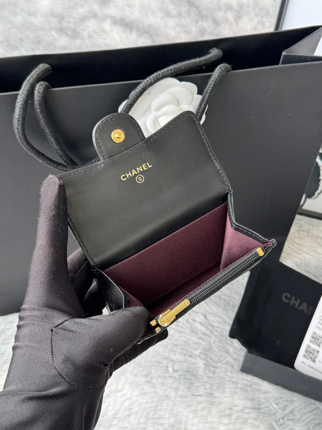 Small quilted flap bag in dark gray/black with gold-tone logo and burgundy interior.