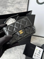 Small quilted flap bag in dark gray/black with stitched panels and gold-tone logo.