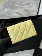 Small quilted flap bag in light yellow with structured front and gold-tone logo.