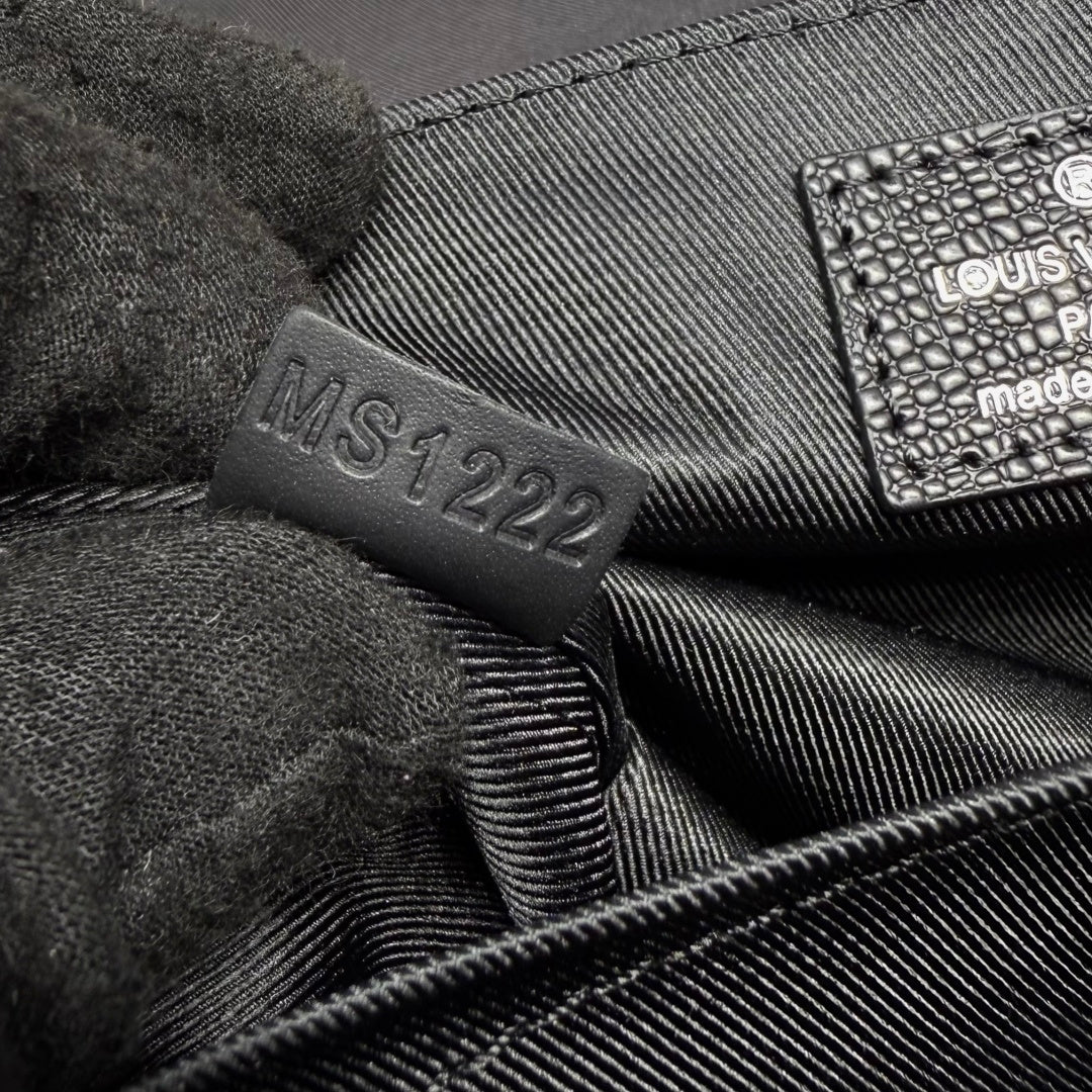 Louis Vuitton interior fabric label marked 'M...122' on dark bag liner.