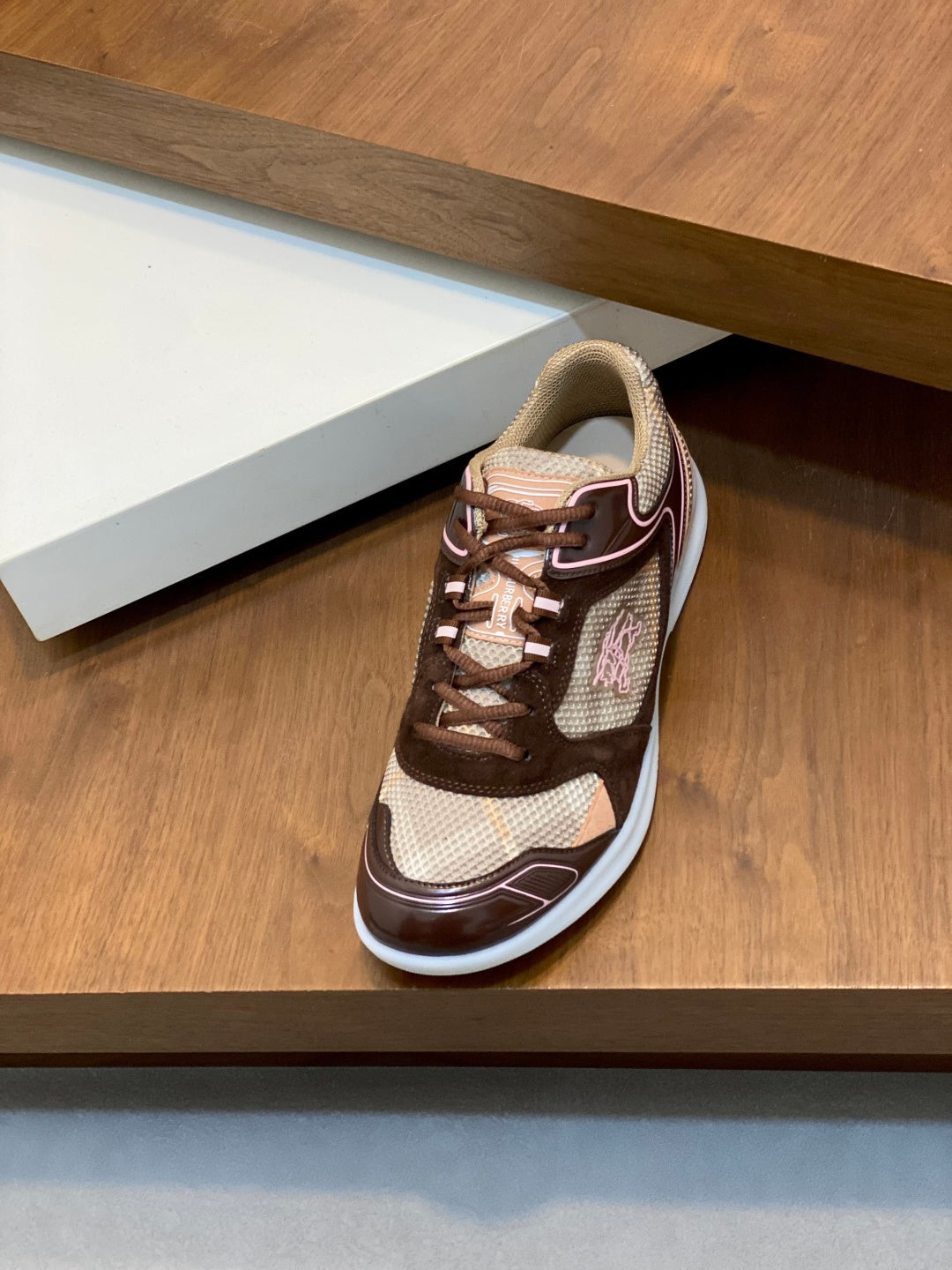 Burberry lace-up sneakers on a shelf, brown and beige uppers with white outsole