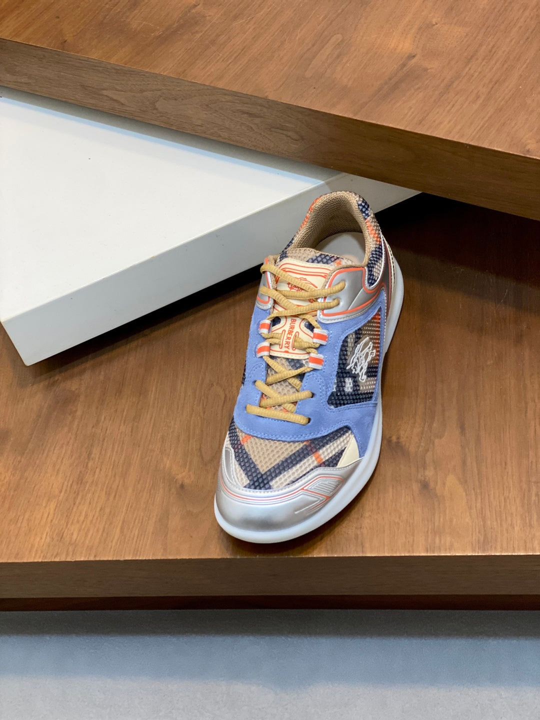 Burberry lace-up sneakers in blue with orange and yellow accents on a shelf