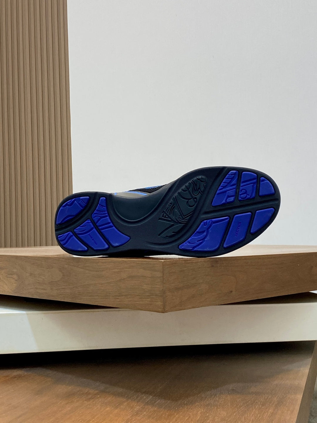 Outsole view of blue and black sneaker with tread pattern, Burberry