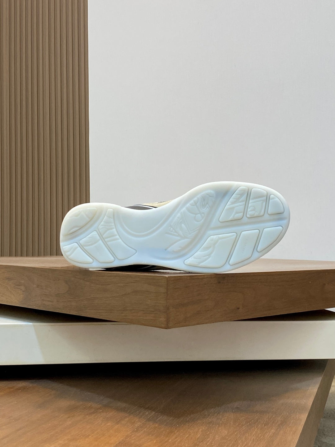 Sneaker outsole, white rubber sole with textured tread, blue accents, heel view