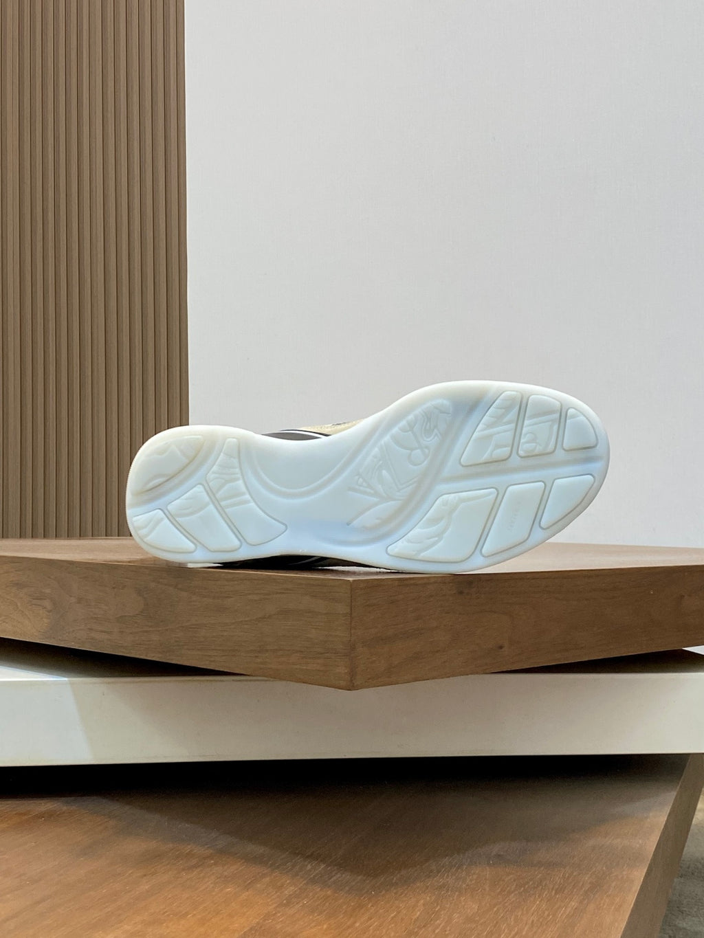 Outsole view of low-top lace-up sneaker in light color with tread pattern