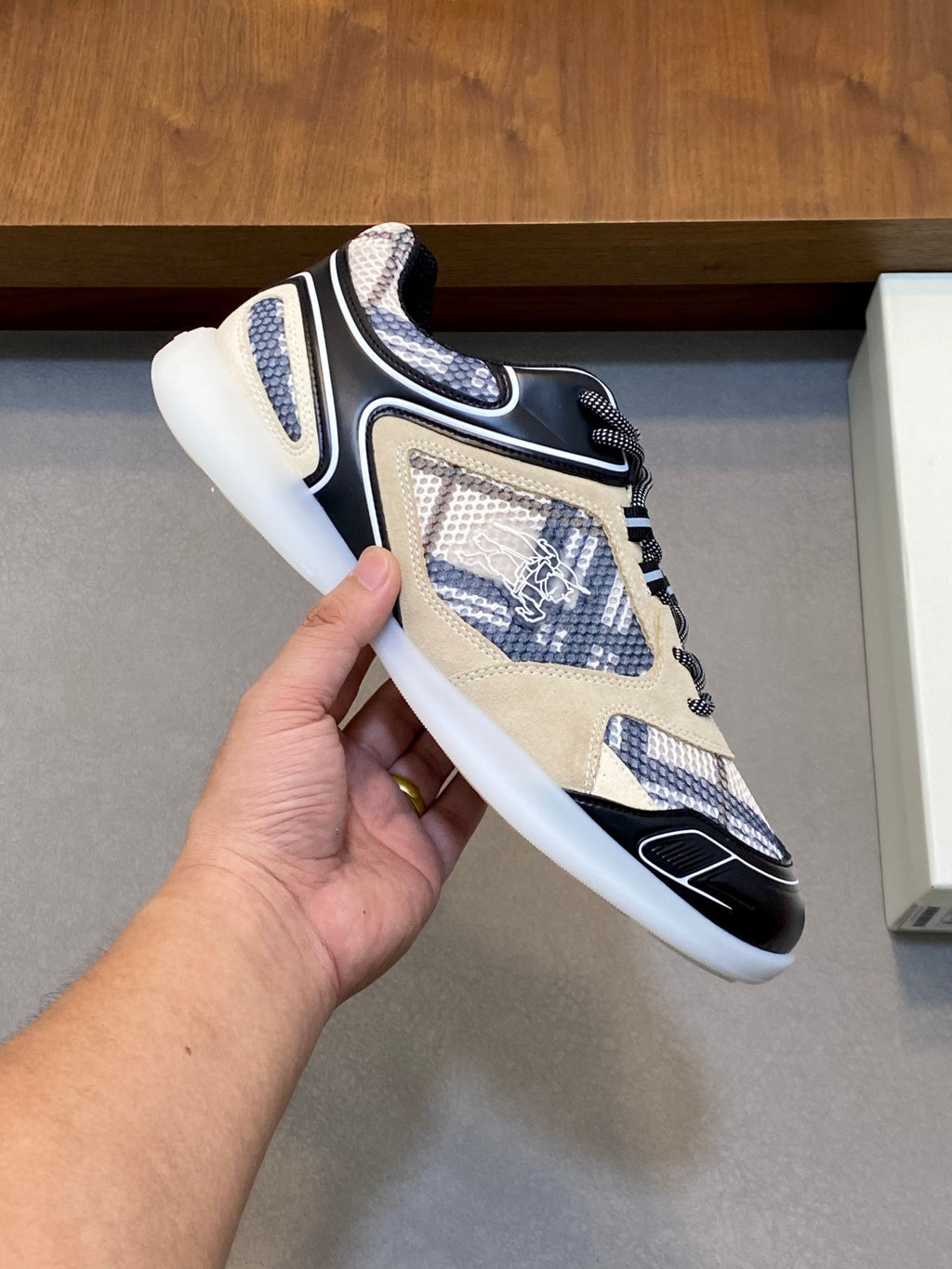 Low-top lace-up sneaker held in hand, beige and navy with patterned fabric