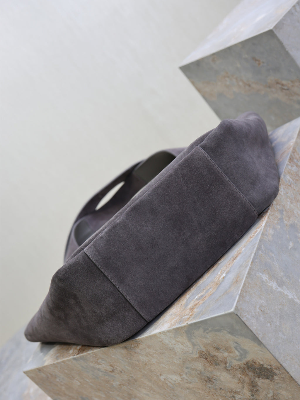 Dark gray suede tote bag with rounded bottom and short handles, side view