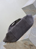 Dark gray suede tote bag with rounded bottom and short handles, side view