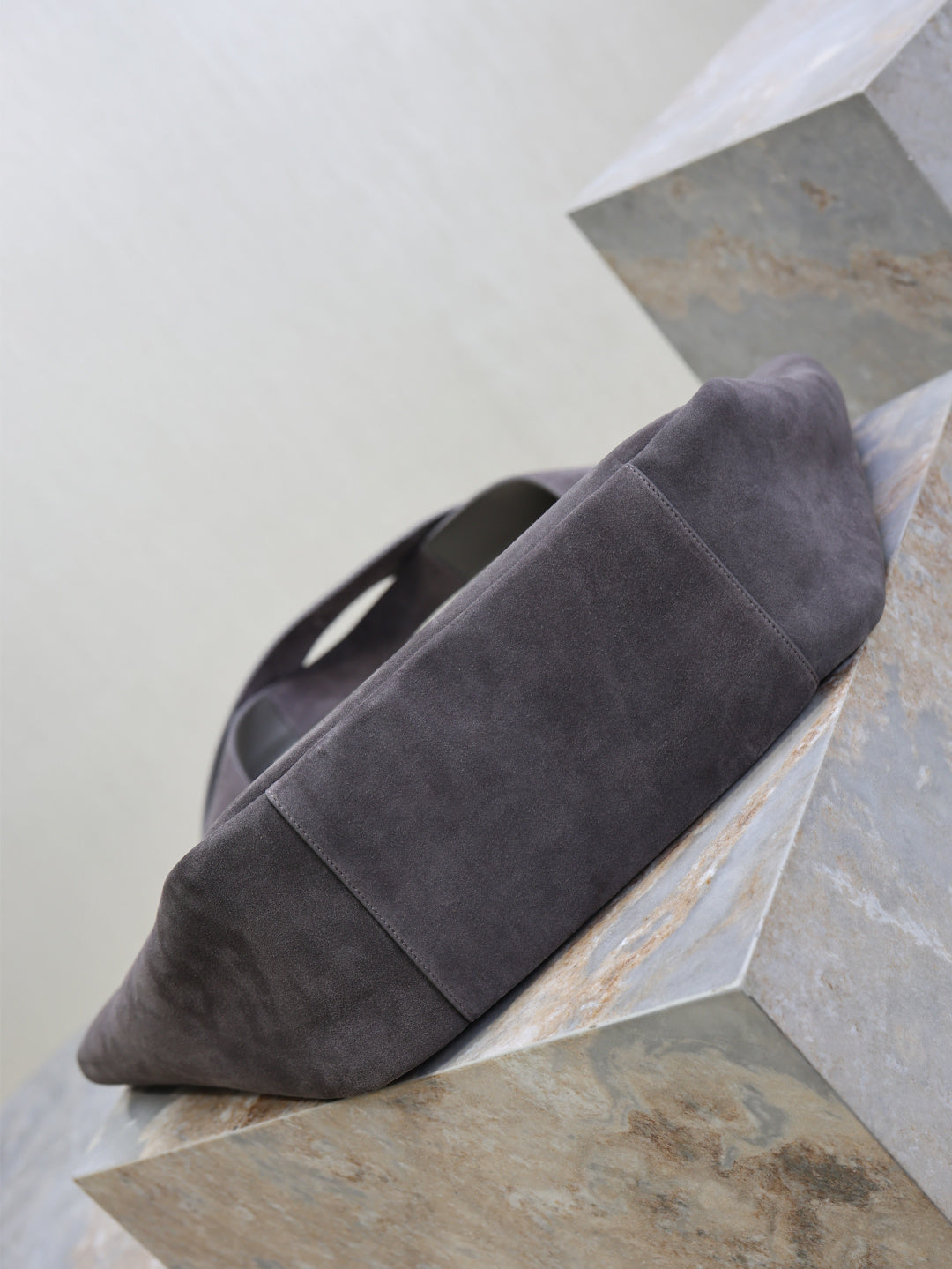 Dark gray suede tote bag with rounded bottom and short handles, side view