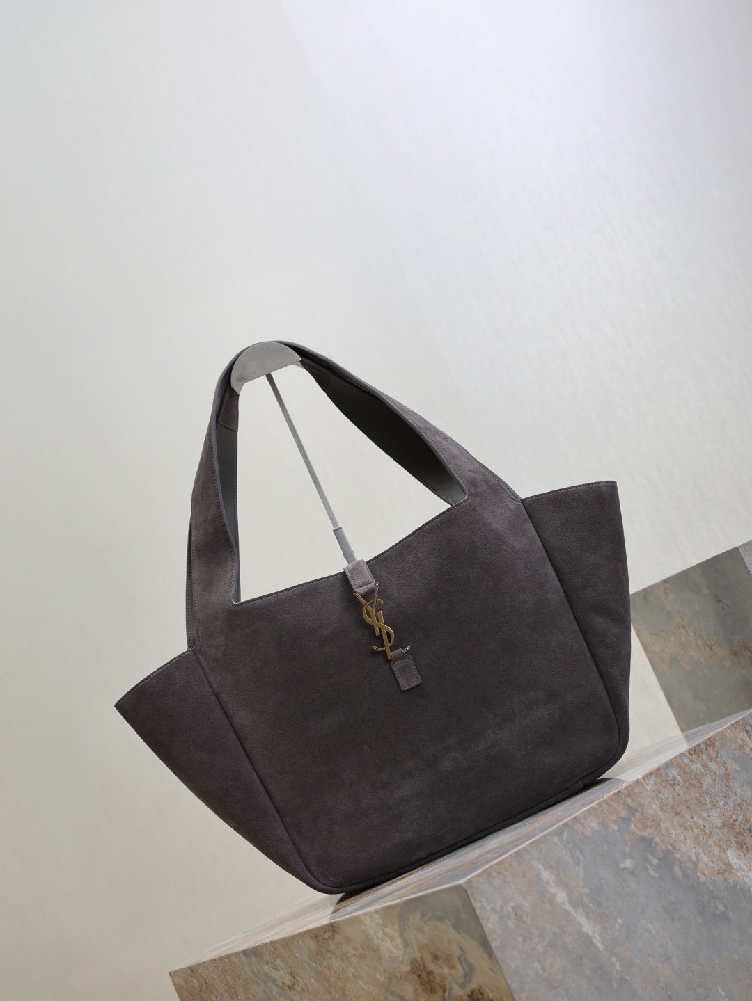 Dark gray suede tote bag angled view, short handles and YSL logo charm