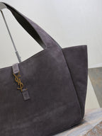 Dark gray suede tote bag close-up of YSL logo charm on front strap