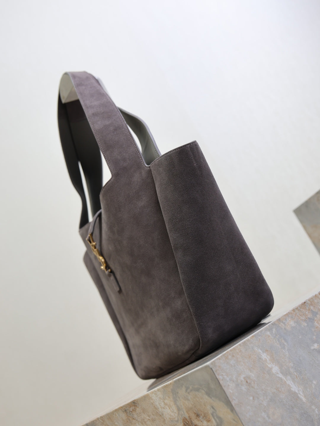 Dark gray suede tote bag with side profile and hanging YSL logo charm