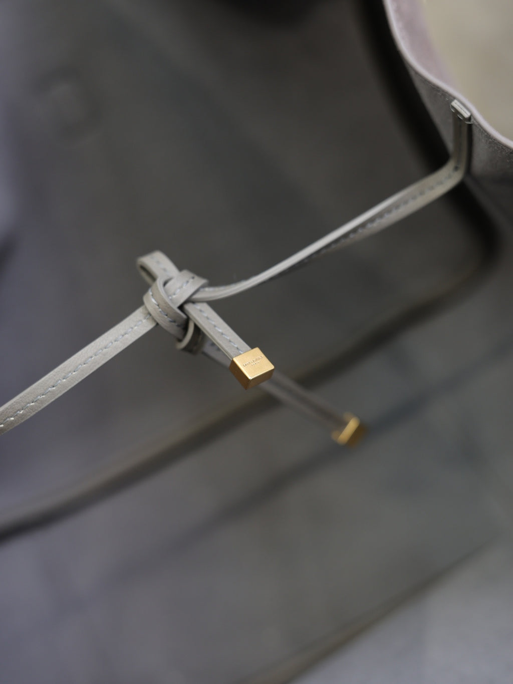 Light gray strap with buckle and gold hardware inside tote bag