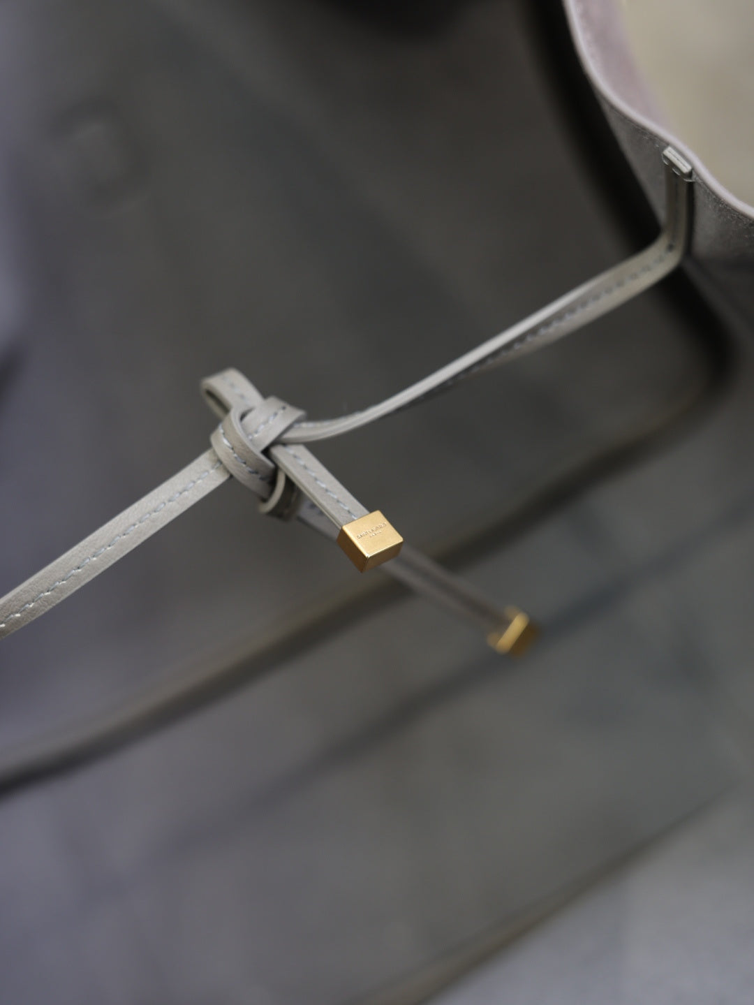 Light gray strap with buckle and gold hardware inside tote bag